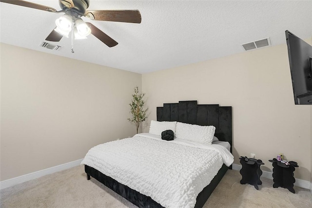 carpeted bedroom with ceiling fan, a textured ceiling, visible vents, and baseboards