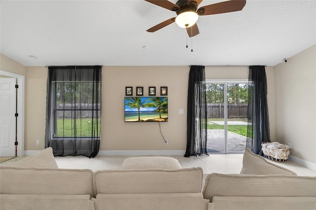 living room featuring a ceiling fan, light tile patterned floors, baseboards, and a textured ceiling