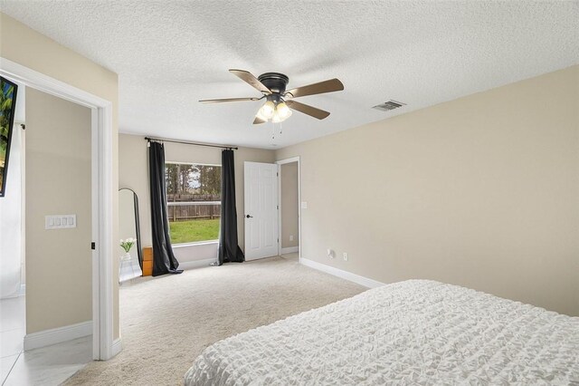 bedroom with light carpet, baseboards, visible vents, a ceiling fan, and a textured ceiling