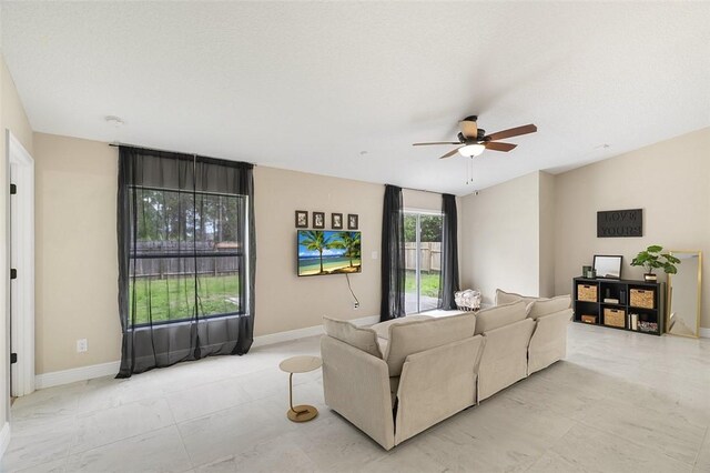 living area featuring ceiling fan and baseboards