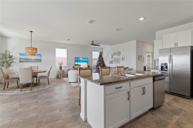 kitchen featuring an island with sink, stainless steel appliances, white cabinetry, and sink