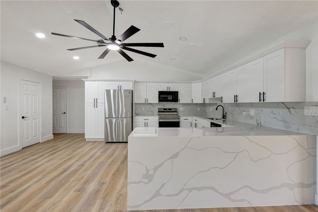 kitchen with light stone counters, stainless steel appliances, white cabinetry, and light hardwood / wood-style flooring