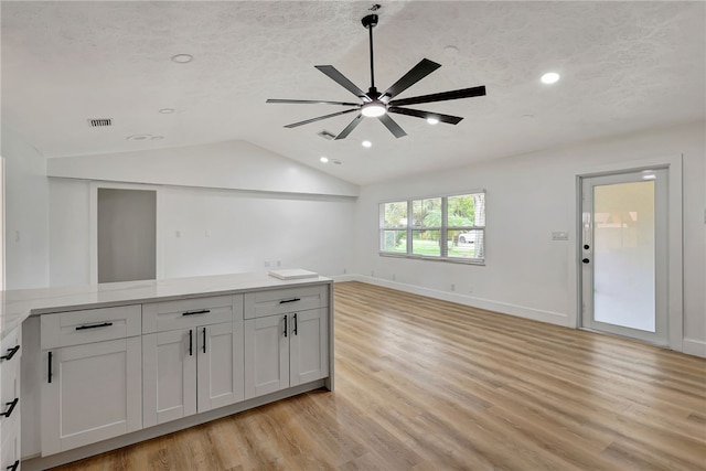 interior space featuring white cabinets, light wood-type flooring, ceiling fan, and lofted ceiling