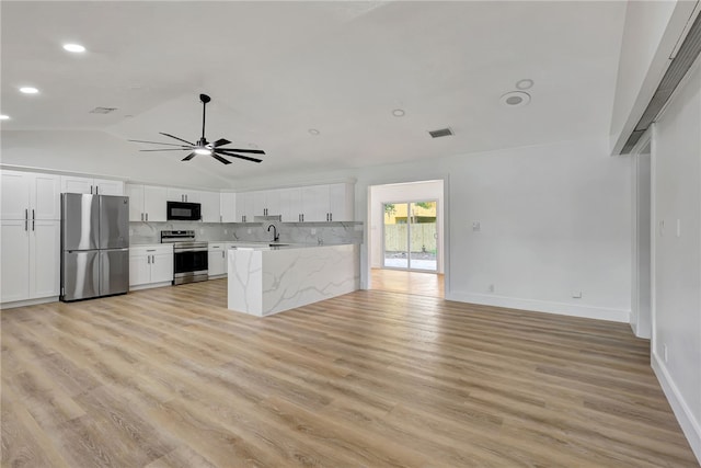 kitchen featuring white cabinets, appliances with stainless steel finishes, light hardwood / wood-style floors, and lofted ceiling