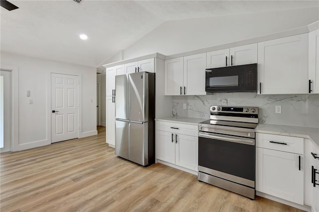 kitchen with appliances with stainless steel finishes, light wood-type flooring, white cabinetry, and lofted ceiling