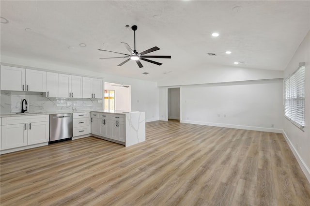 kitchen with white cabinets, sink, vaulted ceiling, stainless steel dishwasher, and light wood-type flooring