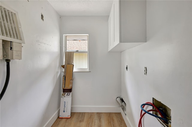 washroom with cabinets, washer hookup, light wood-type flooring, a textured ceiling, and hookup for an electric dryer