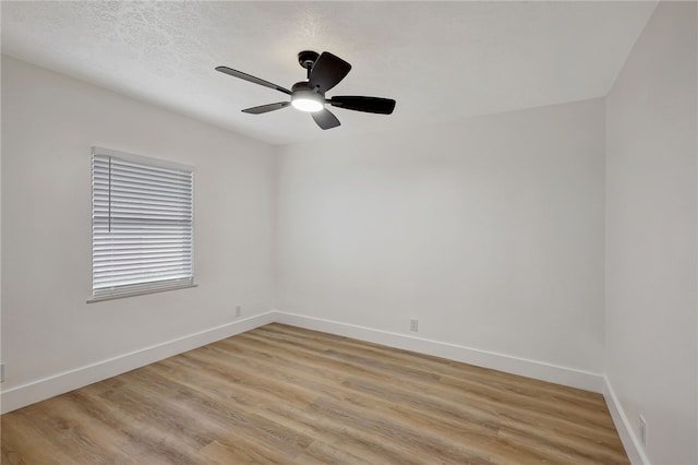 empty room with ceiling fan, light wood-type flooring, and a textured ceiling