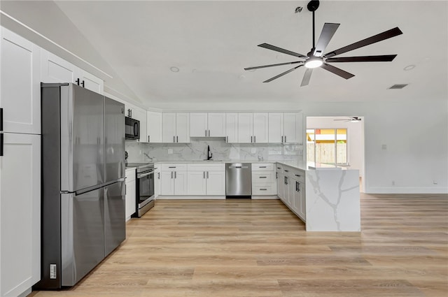 kitchen with stainless steel appliances, sink, light hardwood / wood-style flooring, white cabinetry, and lofted ceiling