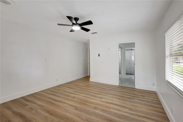 spare room with a textured ceiling, light hardwood / wood-style floors, and ceiling fan