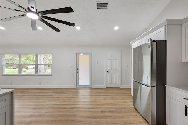 kitchen with stainless steel fridge, white cabinets, light hardwood / wood-style floors, and ceiling fan