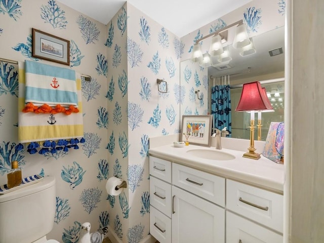 bathroom with visible vents, vanity, toilet, and wallpapered walls