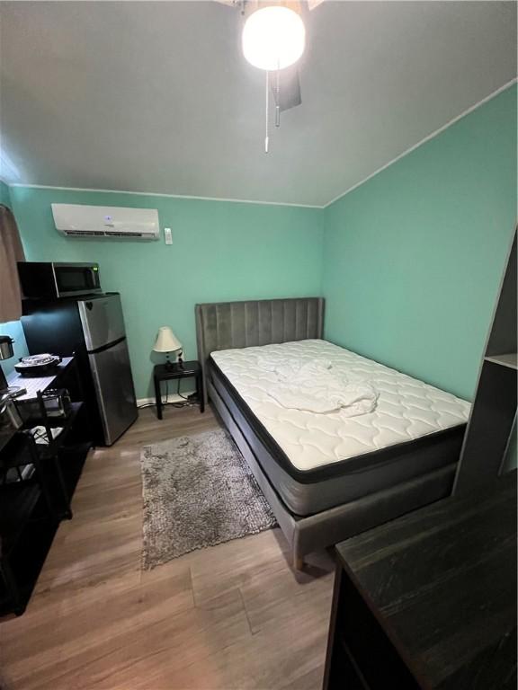 bedroom featuring a wall mounted AC and light hardwood / wood-style flooring