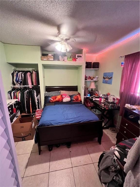 tiled bedroom with ceiling fan and a textured ceiling