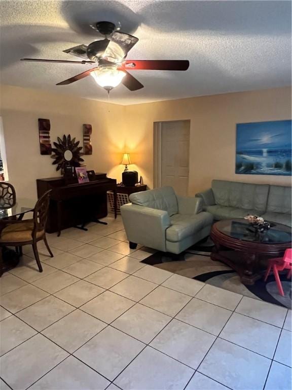 living room with ceiling fan, light tile patterned flooring, and a textured ceiling