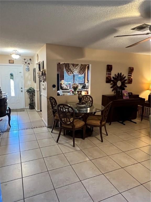 dining space with ceiling fan, light tile patterned floors, and a textured ceiling