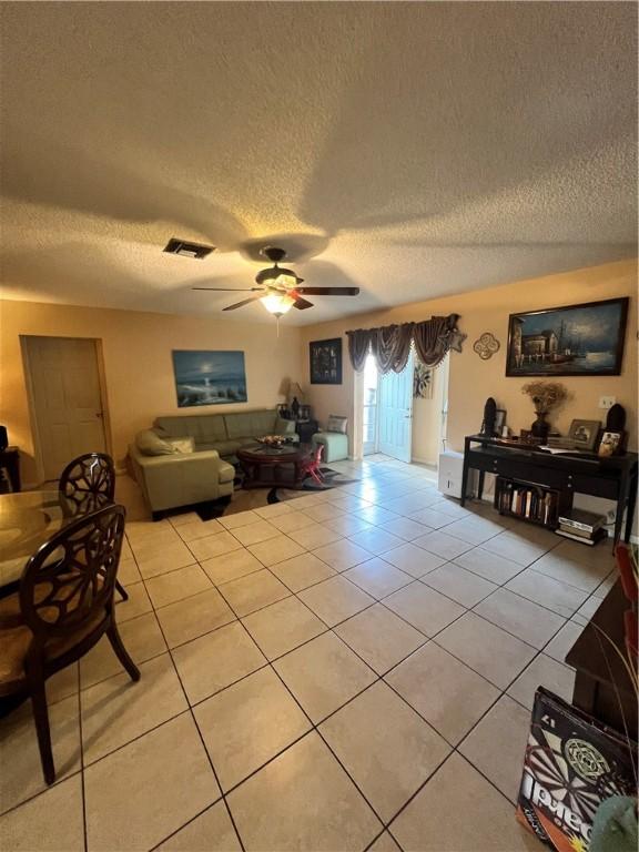 living room featuring light tile patterned floors, a textured ceiling, and ceiling fan