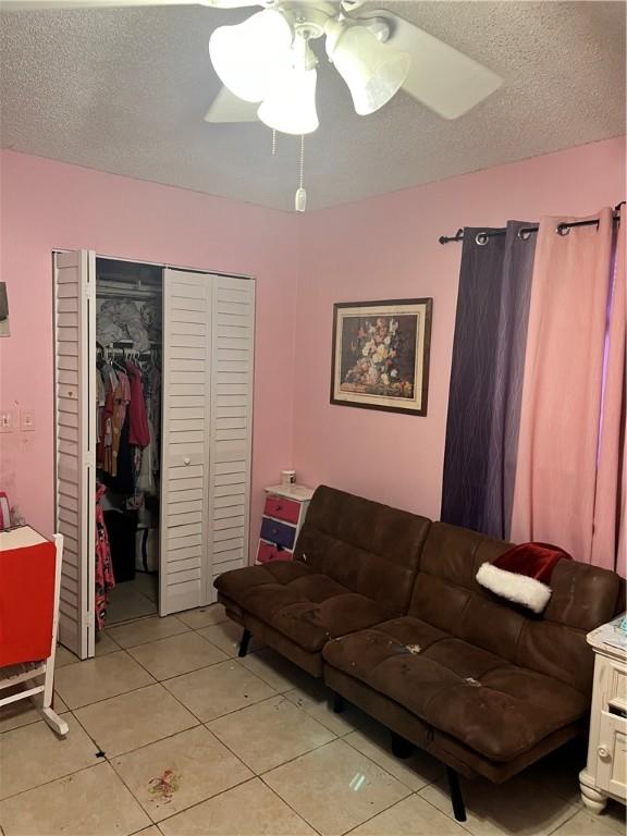 tiled living room with ceiling fan and a textured ceiling