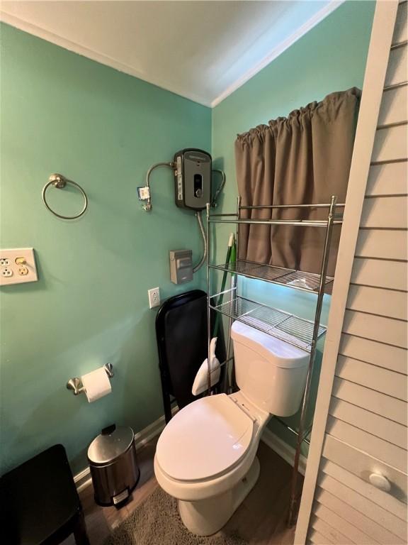 bathroom featuring hardwood / wood-style flooring, toilet, and ornamental molding