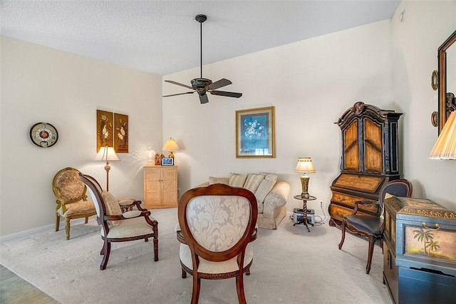 living area with baseboards, carpet flooring, a textured ceiling, and a ceiling fan