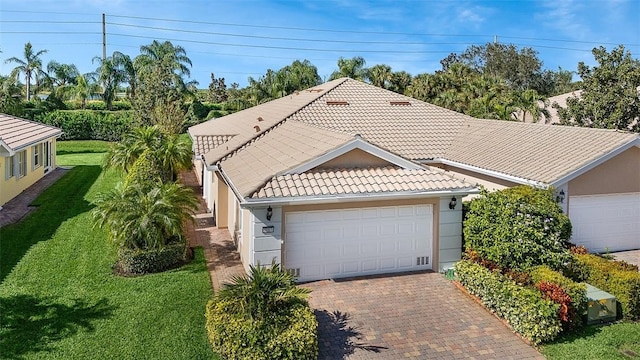 view of front of home featuring stucco siding, driveway, a front yard, and a tiled roof