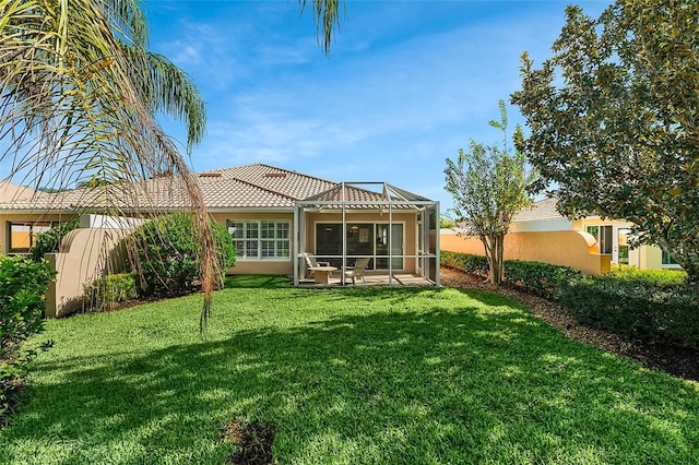 rear view of house featuring stucco siding, a yard, a tile roof, and a patio area