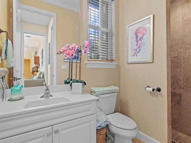 bathroom with tiled shower, vanity, toilet, and crown molding