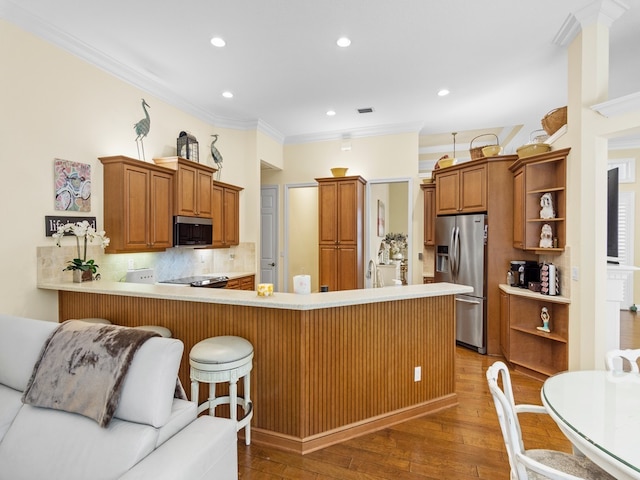 kitchen with kitchen peninsula, appliances with stainless steel finishes, ornamental molding, dark hardwood / wood-style floors, and backsplash