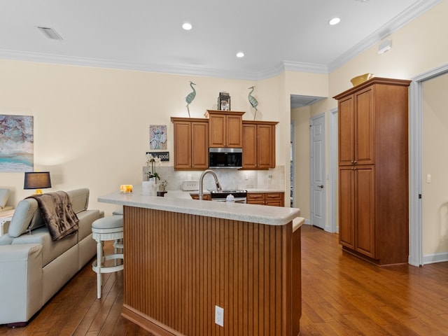 kitchen featuring kitchen peninsula, dark hardwood / wood-style floors, crown molding, a breakfast bar, and appliances with stainless steel finishes