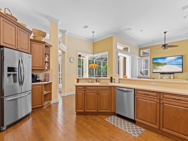 kitchen with stainless steel appliances, hardwood / wood-style floors, ornamental molding, ceiling fan, and pendant lighting