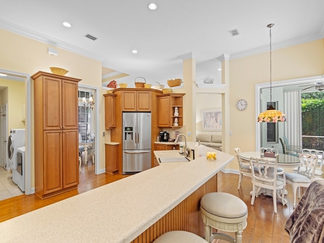 kitchen with hanging light fixtures, sink, a healthy amount of sunlight, and stainless steel fridge