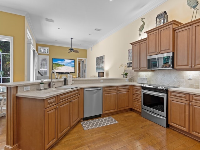 kitchen with stainless steel appliances, light hardwood / wood-style floors, kitchen peninsula, sink, and crown molding