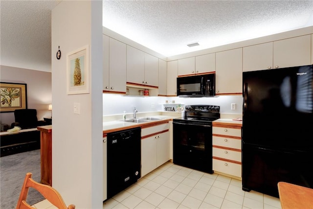 kitchen featuring sink, white cabinets, light tile patterned floors, black appliances, and a textured ceiling