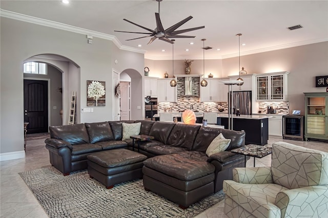 tiled living room with beverage cooler, ceiling fan, and crown molding