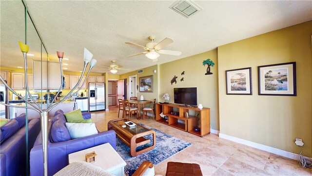 living room with ceiling fan and a textured ceiling