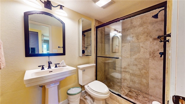 bathroom with a shower with shower door, a textured ceiling, and toilet