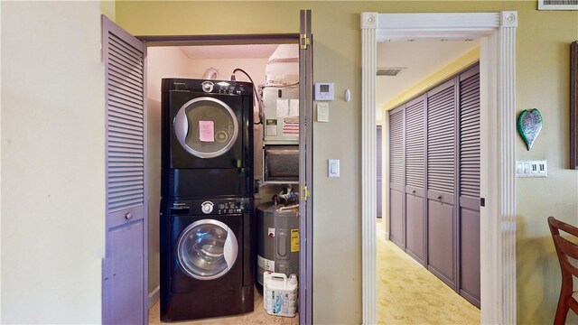 laundry room with electric water heater and stacked washer / drying machine