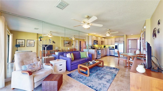 living room featuring ceiling fan and a textured ceiling