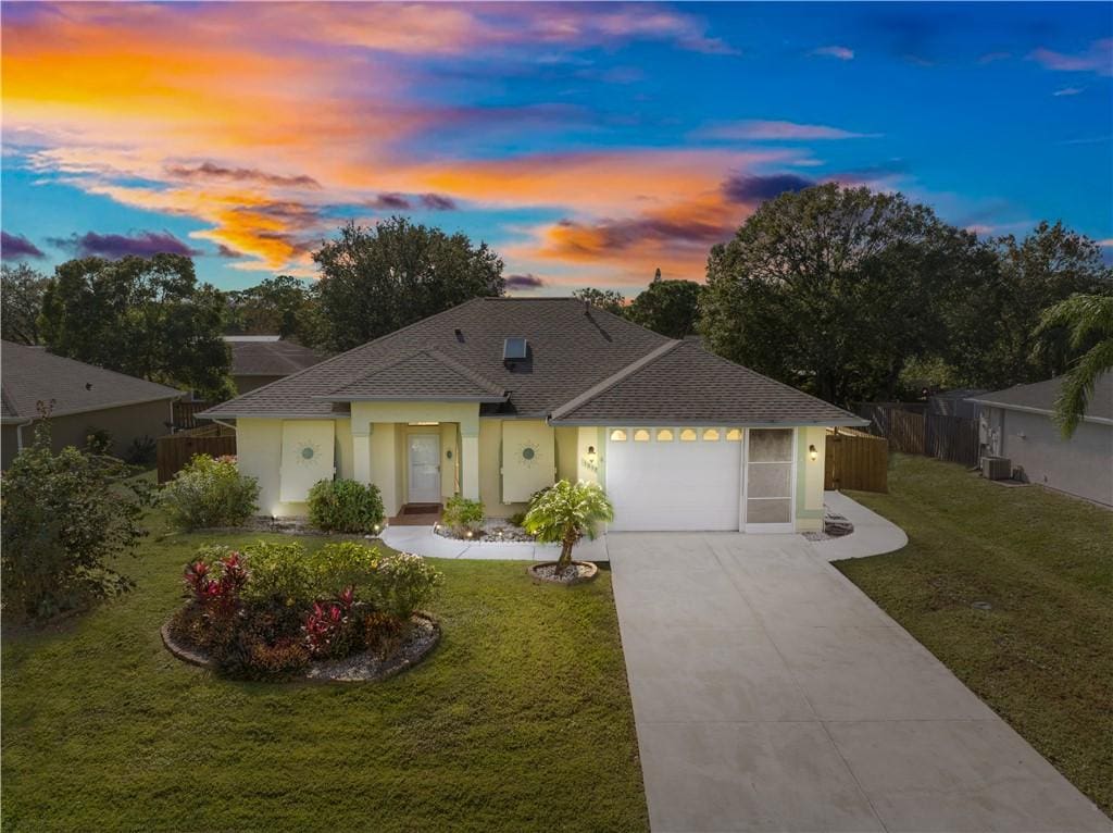 ranch-style home with a lawn, cooling unit, and a garage