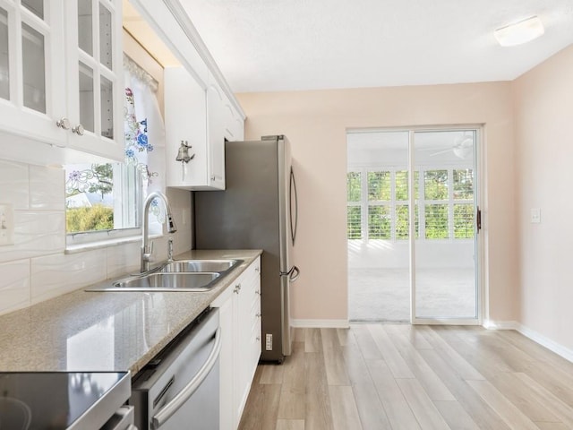 kitchen with sink, appliances with stainless steel finishes, tasteful backsplash, white cabinets, and light wood-type flooring