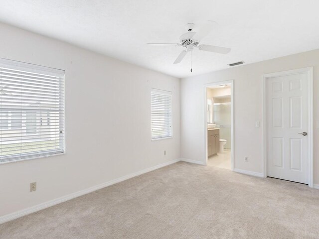 unfurnished bedroom with ensuite bathroom, light carpet, and ceiling fan