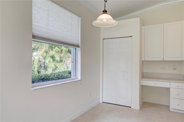 unfurnished bedroom featuring built in desk, crown molding, and light tile patterned flooring