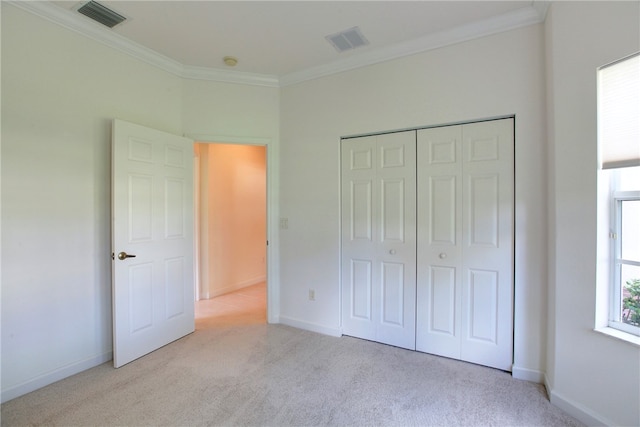 unfurnished bedroom featuring ornamental molding, light carpet, and a closet