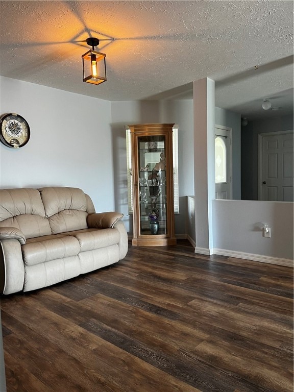 unfurnished living room featuring dark wood-type flooring and a textured ceiling