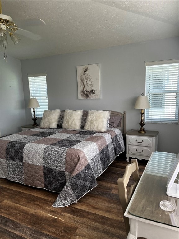 bedroom with ceiling fan, a textured ceiling, and dark hardwood / wood-style flooring