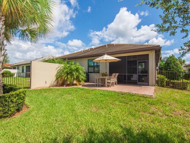 back of property with a patio, a sunroom, and a lawn