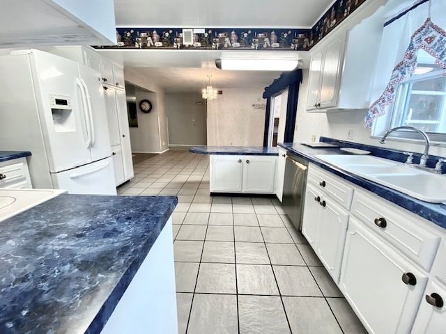 kitchen featuring dishwasher, sink, an inviting chandelier, white cabinetry, and white refrigerator with ice dispenser