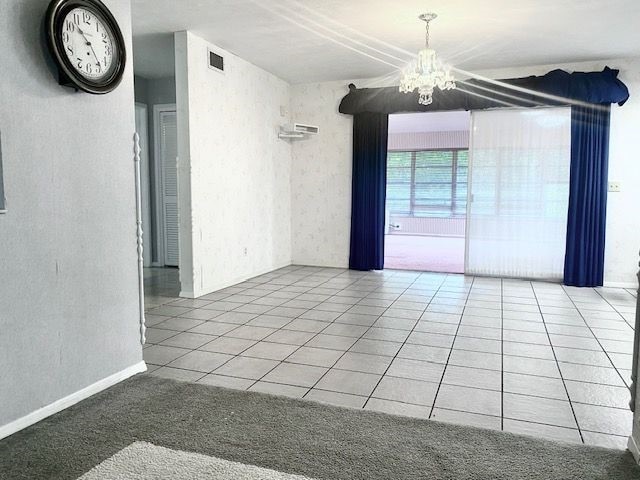 tiled spare room featuring a chandelier