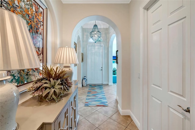 foyer entrance with an inviting chandelier, crown molding, and light tile patterned flooring