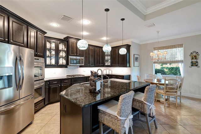 kitchen featuring a kitchen island with sink, decorative light fixtures, light tile patterned flooring, dark brown cabinetry, and stainless steel appliances